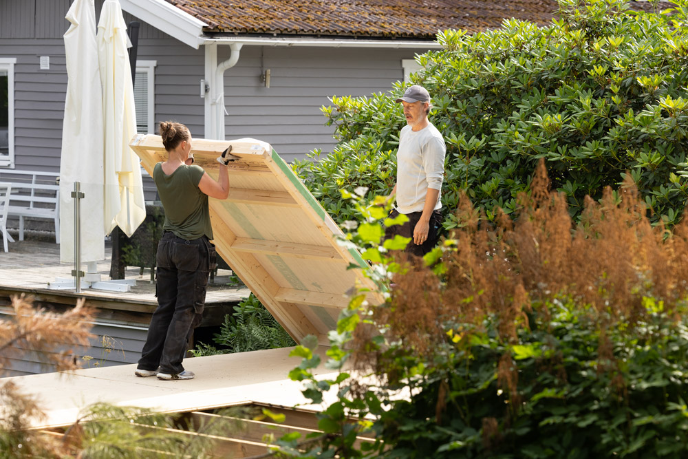 2 personer lyfter upp en väggmodul till attefallshus från Skånska Byggvaror