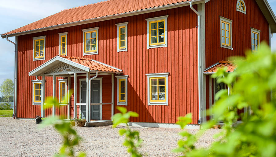 Ett rött hus med gula fönster från Elitfönster.